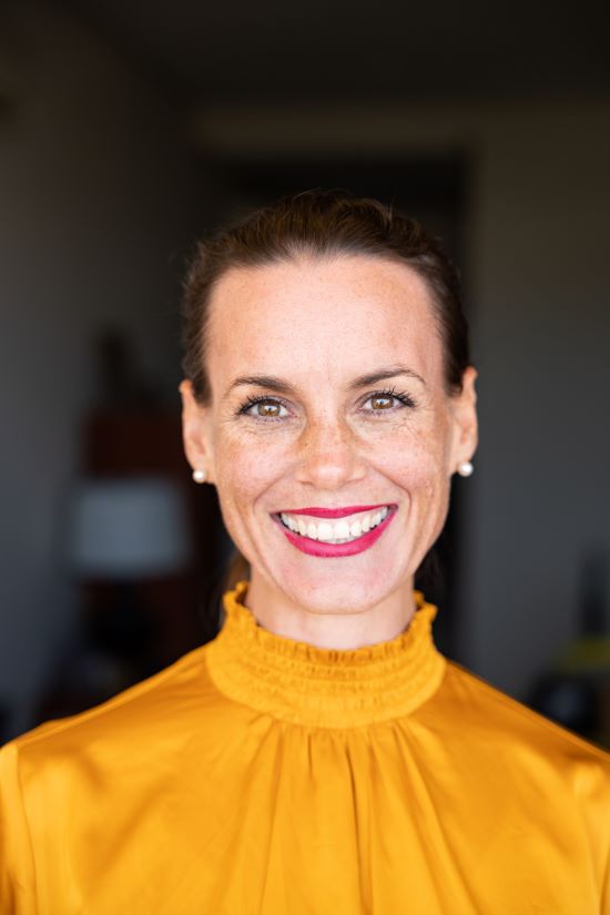 Belinda Spratt smiling, wearing a mustard-yellow blouse