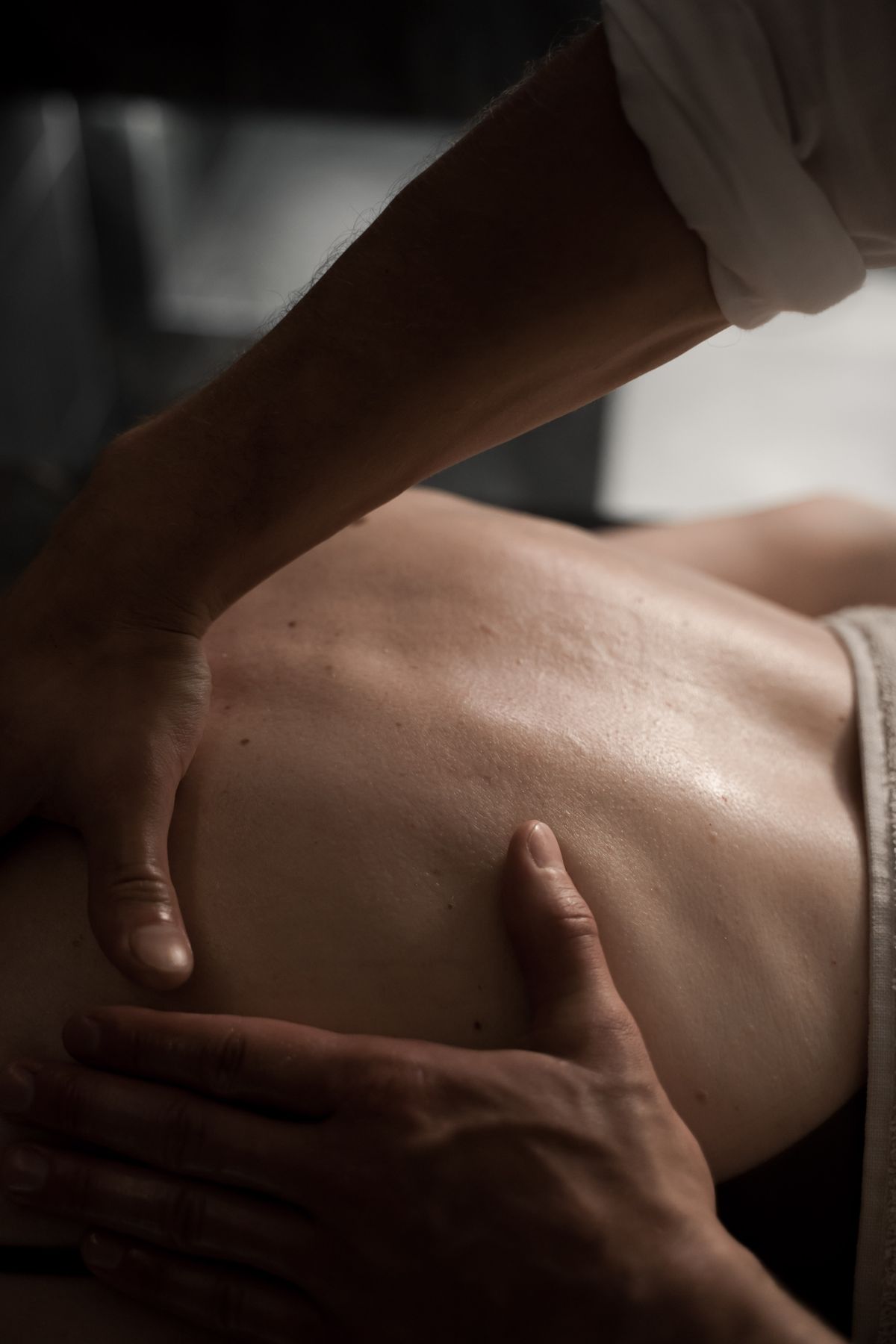 Close-up of hands giving a back massage, with the client comfortably draped