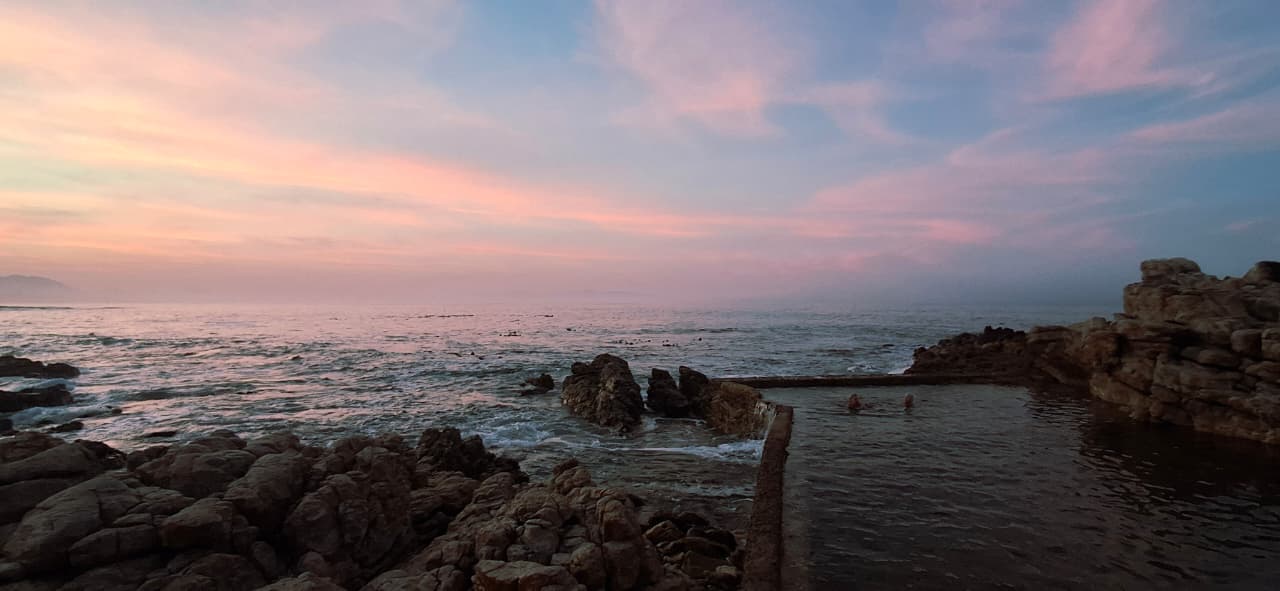 A coastal tidal pool and rocky shoreline beneath a pink evening sky, supplied by Belinda