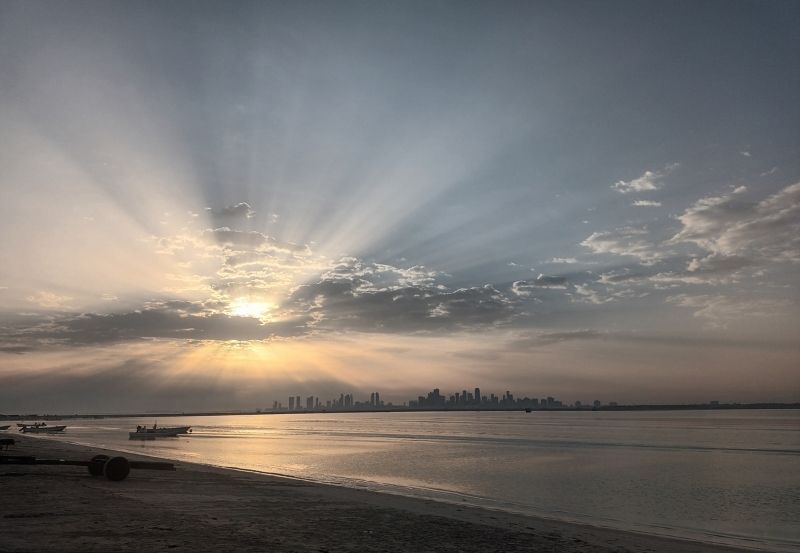 Sun rays breaking through clouds over a calm sea at sunrise